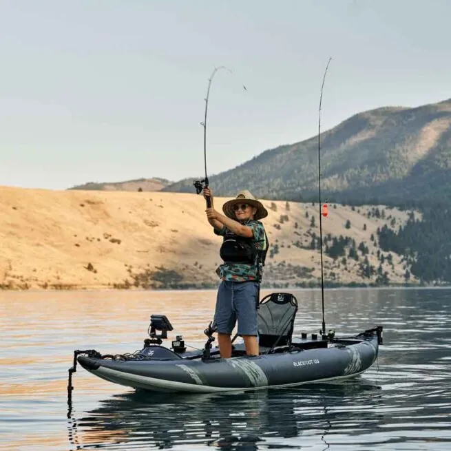 A man standing up fishing in the new 2021 Aquaglide Blackfoot Angler 130 inflatable kayak.
