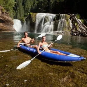 Aquaglide Klickitat inflatable two seat kayak in blue on the water with two people paddling.