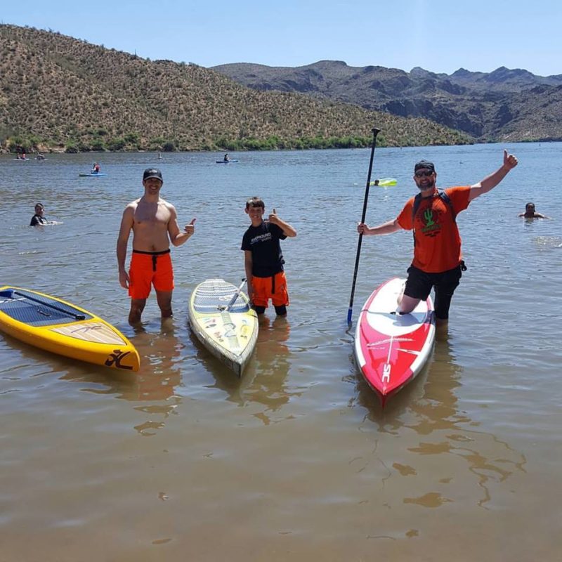 Saguaro lake side with three paddleboarders.