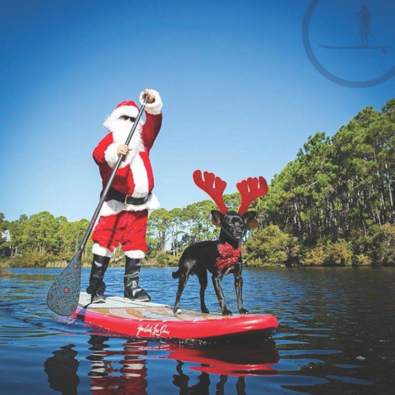 Santa and his dog reindeer paddling on his Yolo Board SUP.
