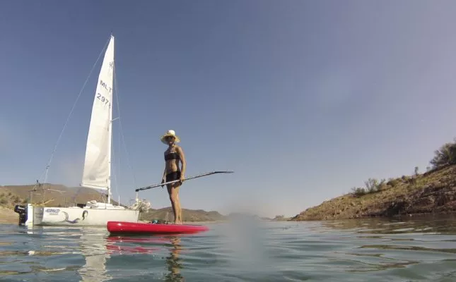 Paddleboarder next to a sailboat at Lake Pleasant, Arizona.