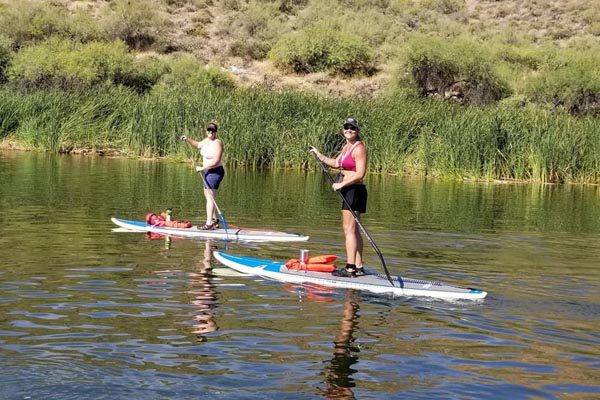 To ladies paddleboarding on Canyon lake in Arizona with Riverbound Sports.