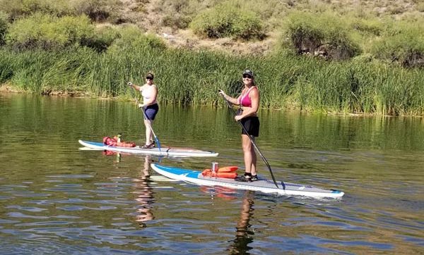 To ladies paddleboarding on Canyon lake in Arizona with Riverbound Sports.