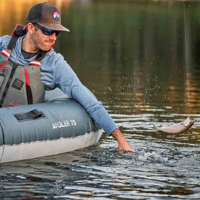 A fisherman with fish paddling the Backwoods Angler 75 ultralight inflatable kayak.