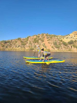 Two ladies taking paddleboarding lessons at Saguaro Lake by Riverbound Sports.