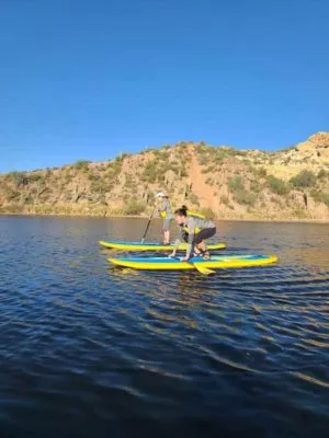 Two ladies taking paddleboarding lessons at Saguaro Lake by Riverbound Sports.