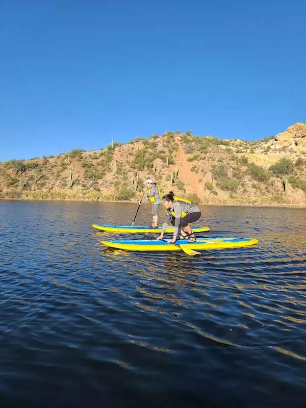 Two ladies taking paddleboarding lessons at Saguaro Lake by Riverbound Sports.