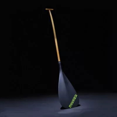 The Puakea Designs Hopu OC6 paddle with a carbon blade, a green Puakea logo, and a double-bend wood shaft. Available at Riverbound Sports in Tempe, Arizona.