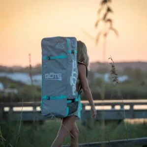 Woman carrying Bote paddleboard bag at sunset. Riverbound SPorts Paddle Company