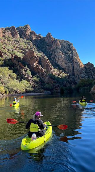 Kayakers on serene water against a mountainous backdrop. Riverbound Sports Paddle Company bachelorette party