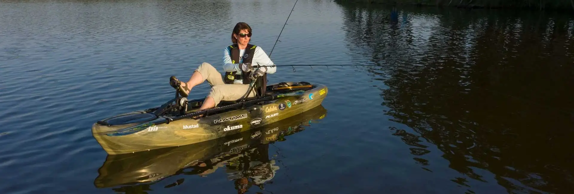 A person fishing from a Native Watercraft Slayer Propel 10 kayak on calm water. Riverbound Sports Paddle Company