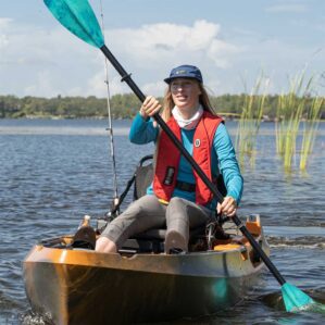 Woman kayaking and fishing on a serene lake