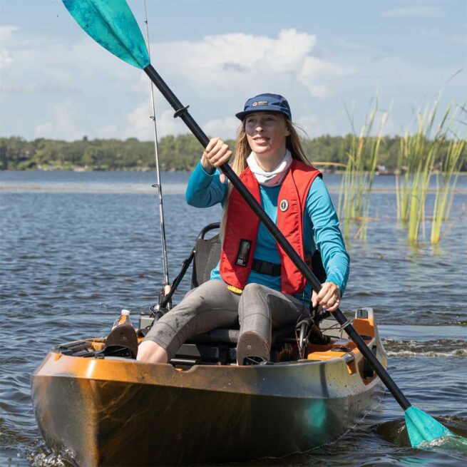 Woman kayaking and fishing on a serene lake