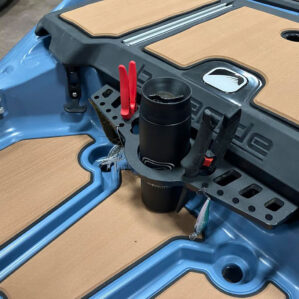 A close-up showing the Bonafide XTR Tool Caddy organized with fishing gear. A black insulated tumbler sits in the center, while red and black pliers are stored in side slots and several fishing lures hang from small integrated holes along the front edge.